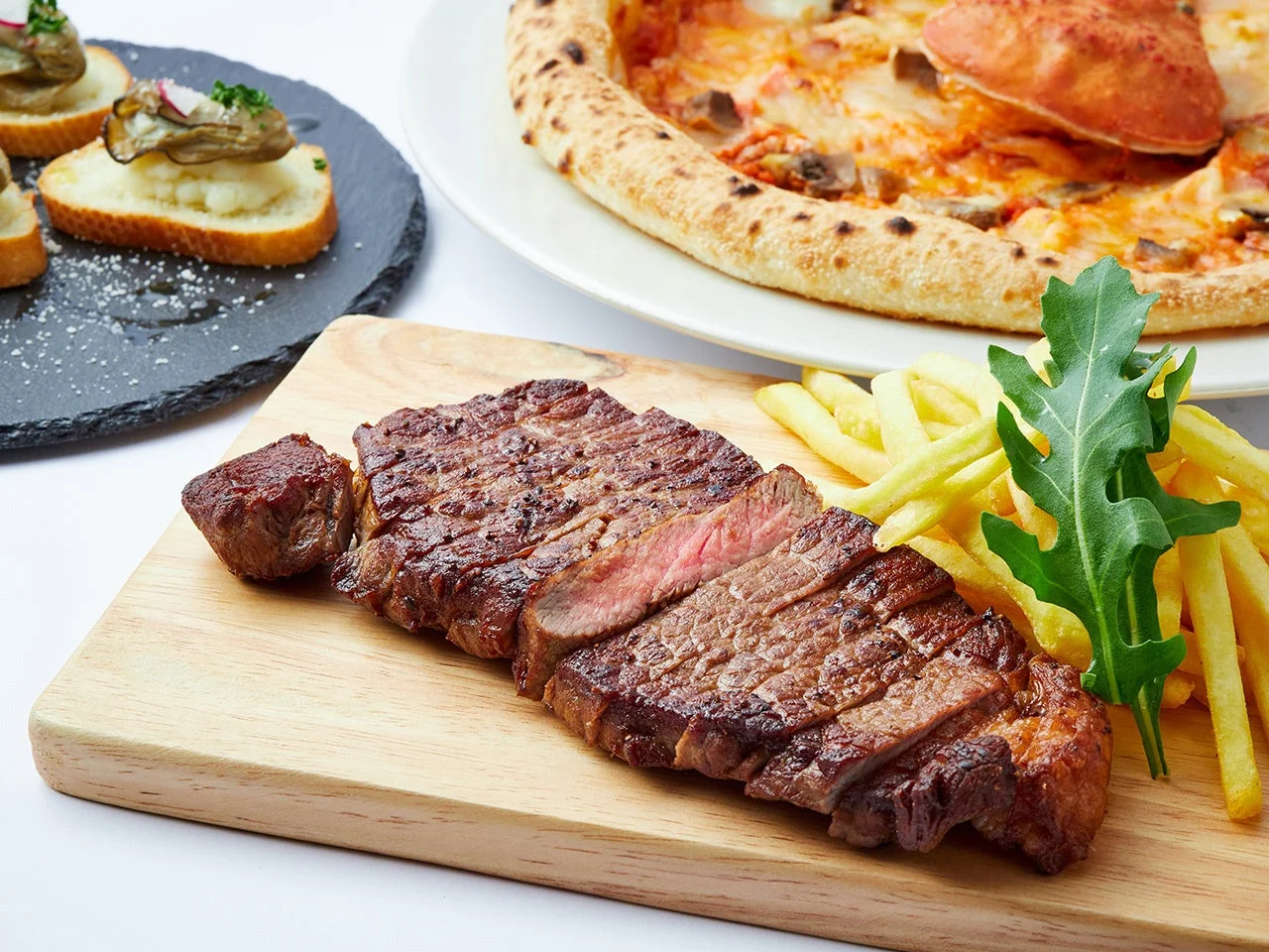 切り分けられたステーキとフライドポテト、ルッコラが盛り付けられた木製ボード