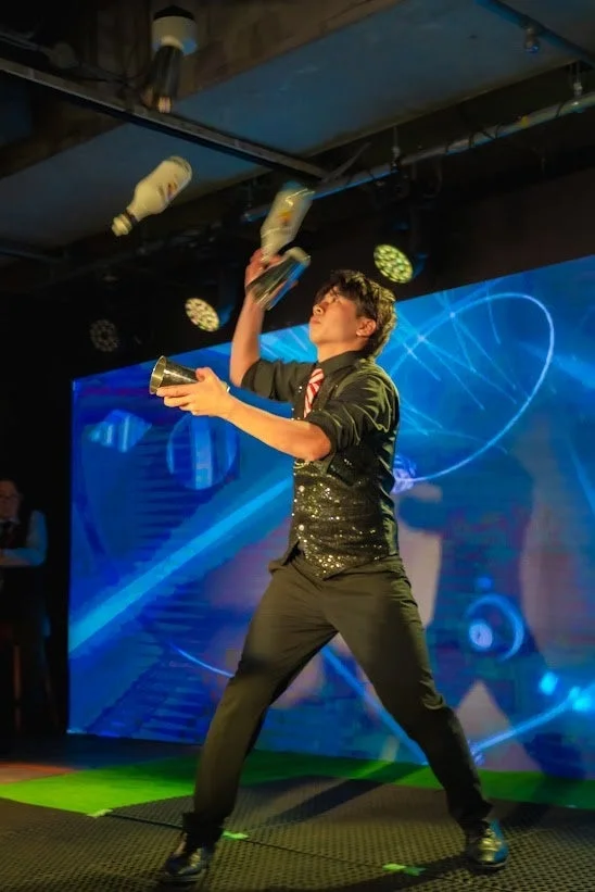 舞台上でボトルとシェーカーを操るバーテンダー