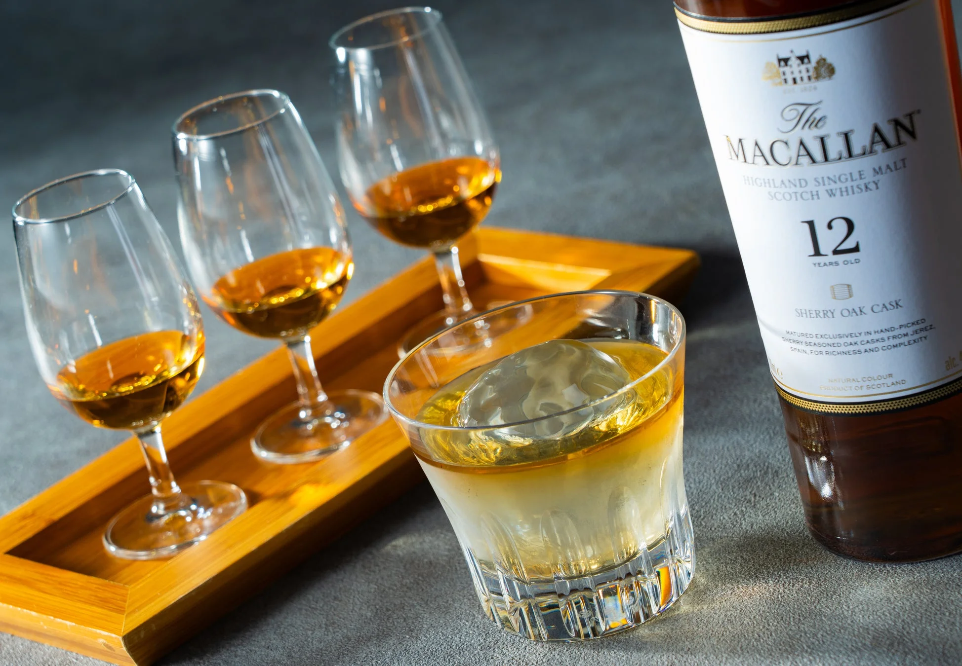 マッカラン12年シェリーオークカスクのボトルと、テイスティンググラス3つ、ロックグラス1つが並べられたウイスキーのイメージ