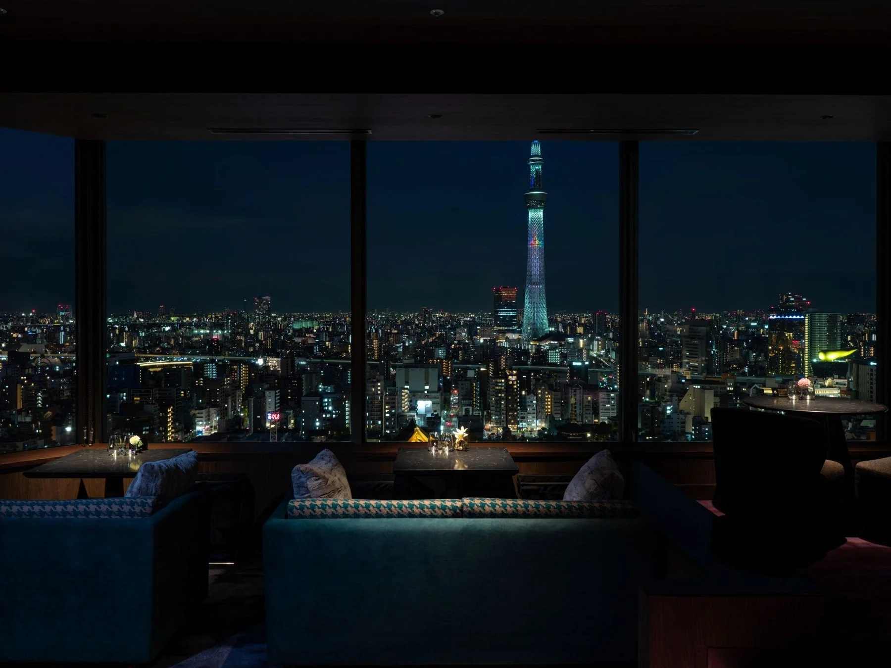 高層階のラウンジから、ライトアップされた東京スカイツリーと煌めく都市の夜景を一望する様子