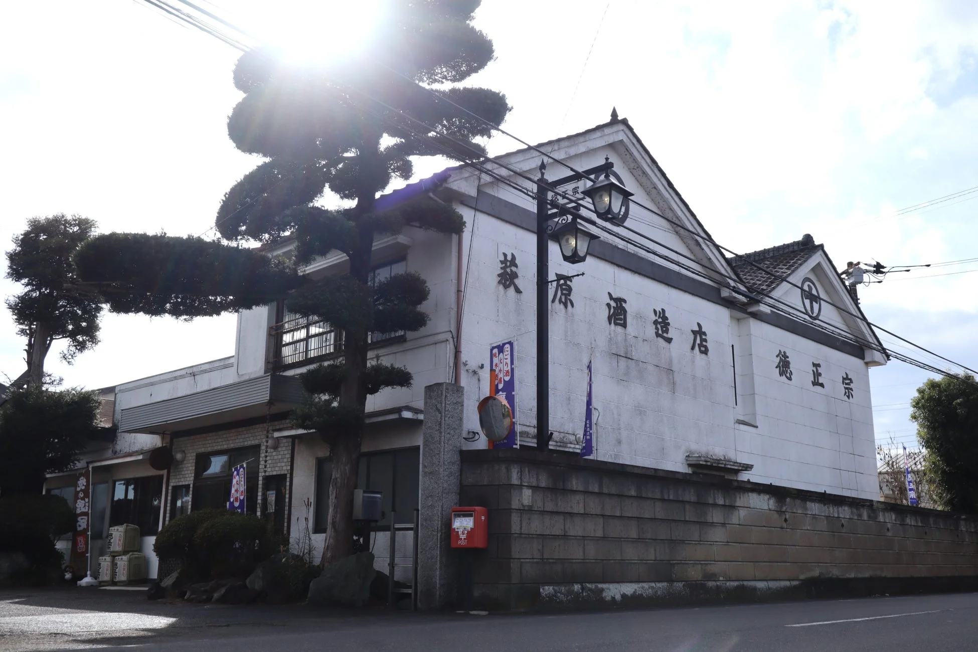 「萩原酒造店」と書かれた伝統的な日本家屋の酒蔵。手前には赤い郵便ポストが見えます。