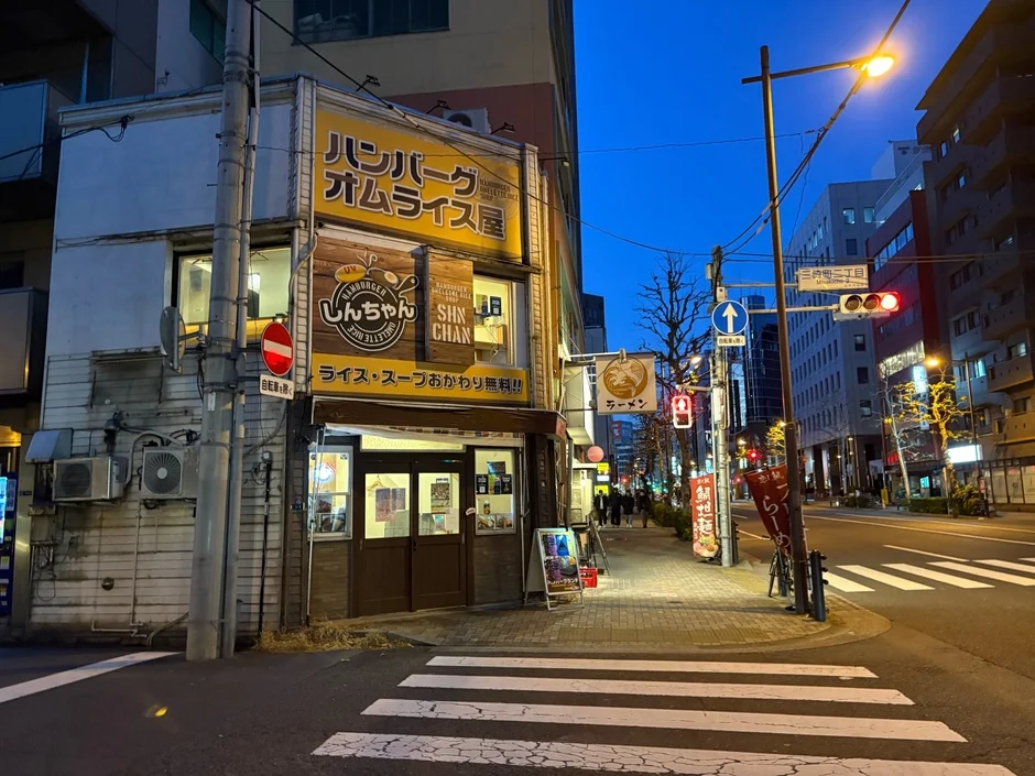 夕暮れの日本の街角にある「ハンバーグ オムライス屋 しんちゃん」