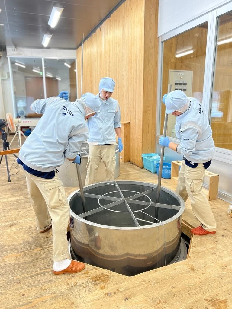 大きな醸造タンクで作業する蔵人たち