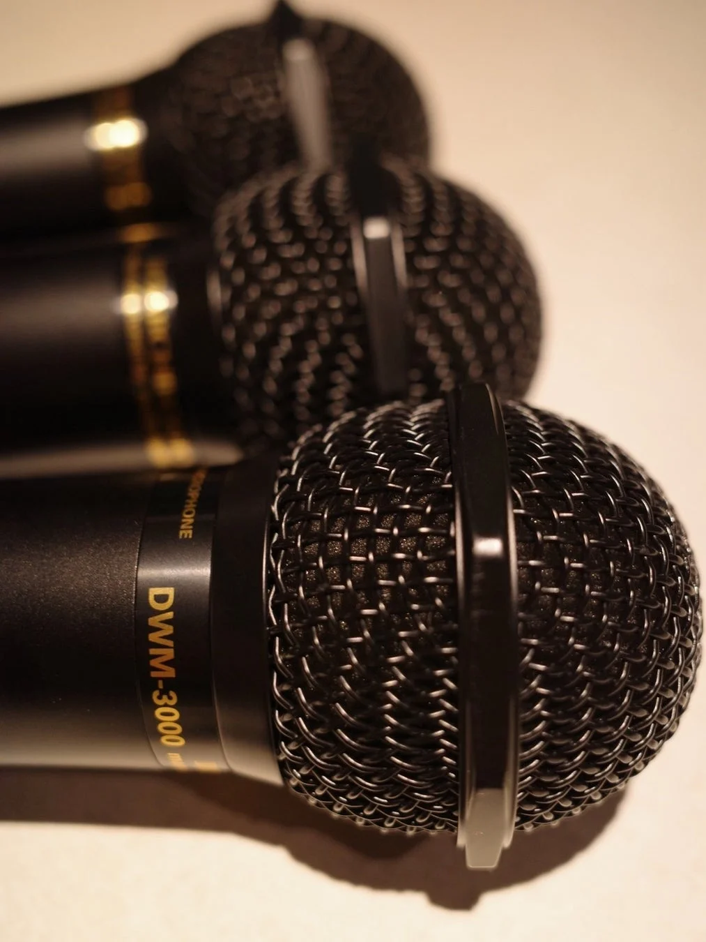 複数の黒いマイクが並べられており、手前のマイクに焦点が合ってDWM-3000という型番が見えます。