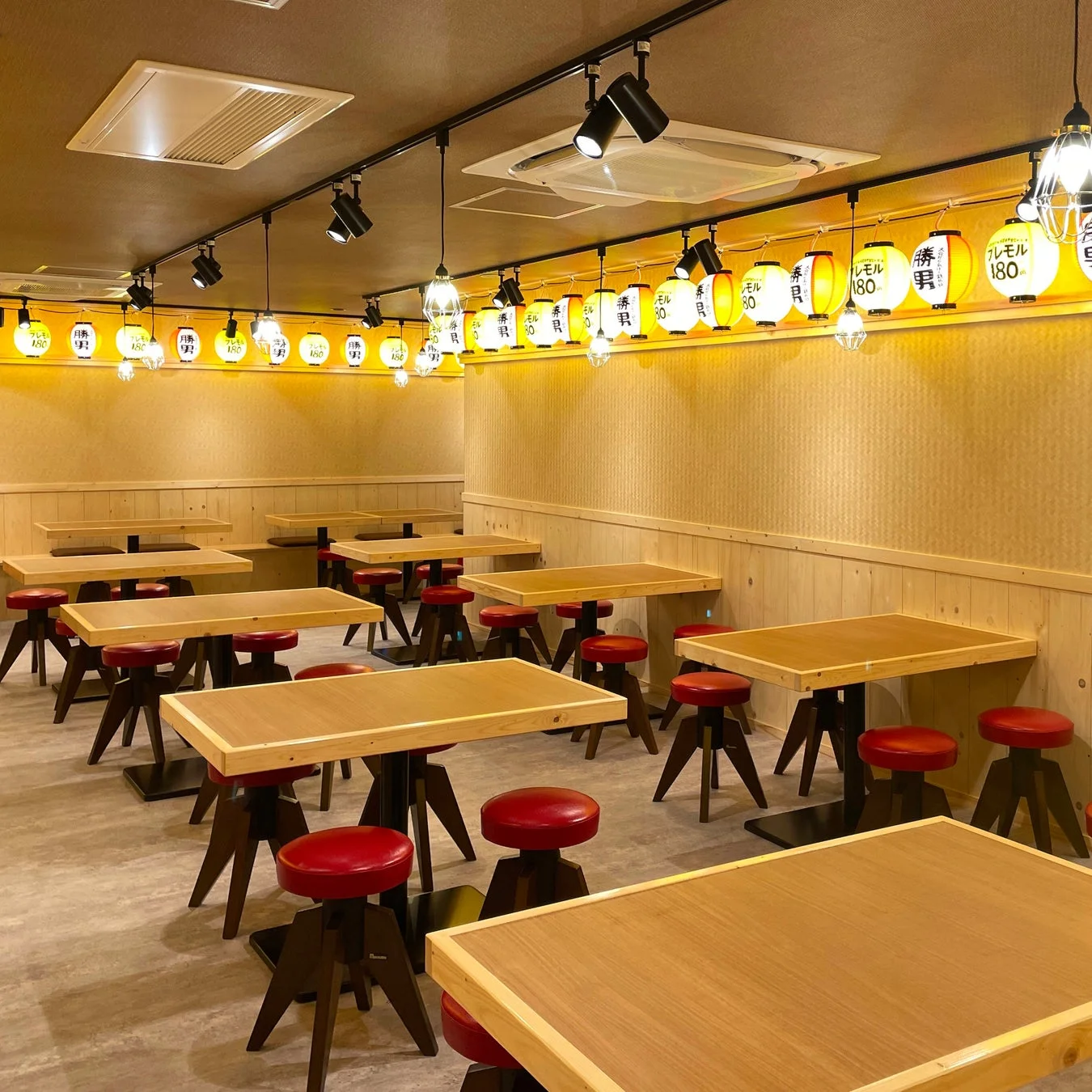 勝男のテーブル席と提灯が並ぶ店内