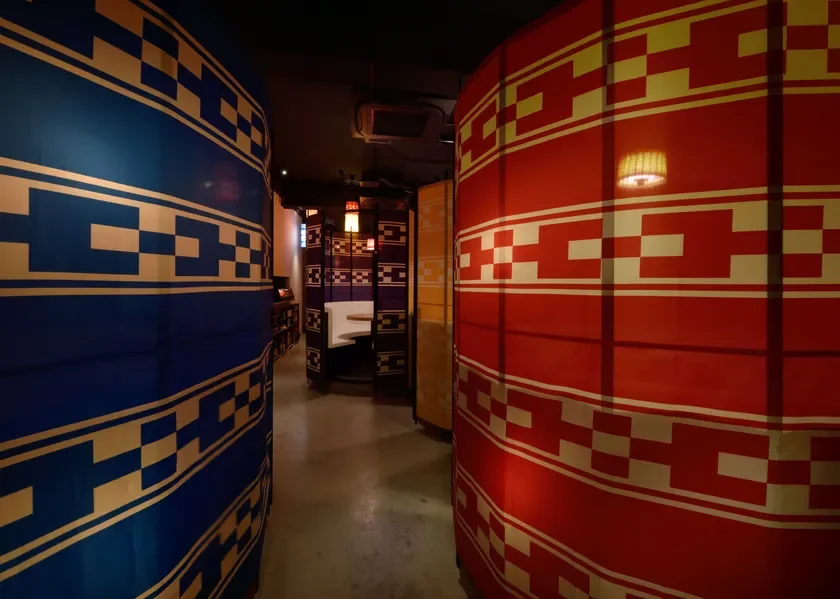 幾何学模様の青と赤の大きな衝立で仕切られた、和モダンな雰囲気の飲食店内部