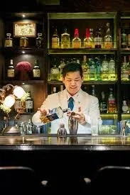 白衣を着たバーテンダーがカクテルを作っている様子