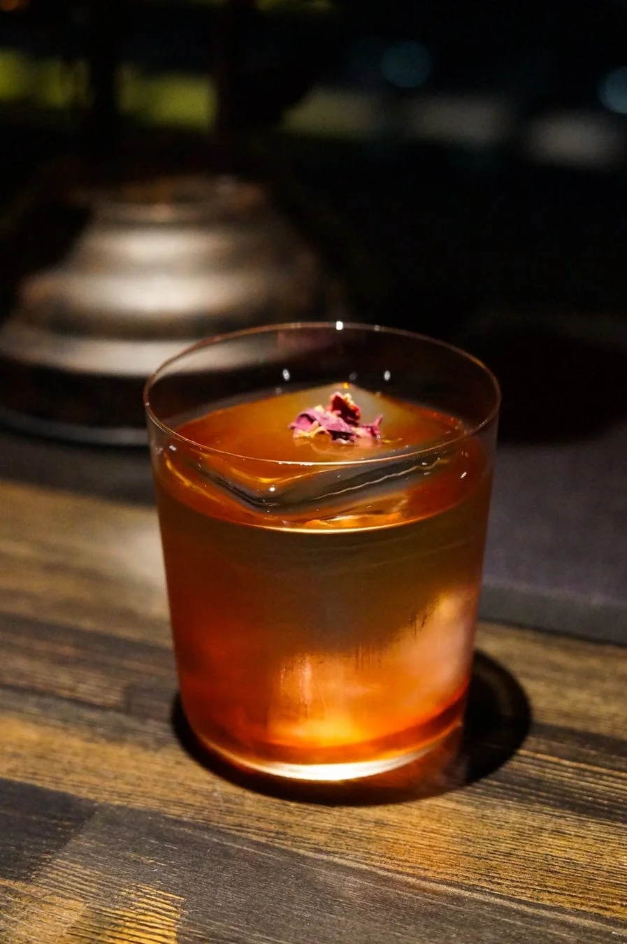 暗い照明の中で木製のテーブルに置かれたカクテルの写真