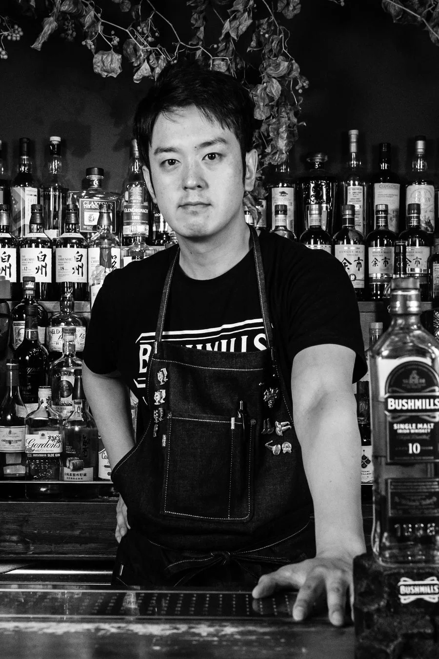 ウイスキーボトルを背景にしたバーテンダー