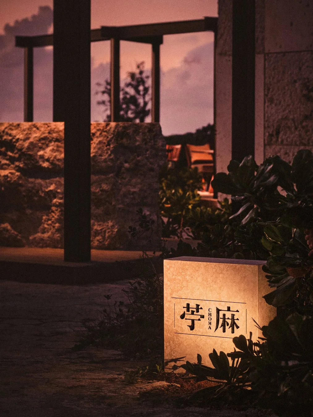 夕暮れ時、庭園に設置された「苧麻 CHOMA」と書かれた光る看板