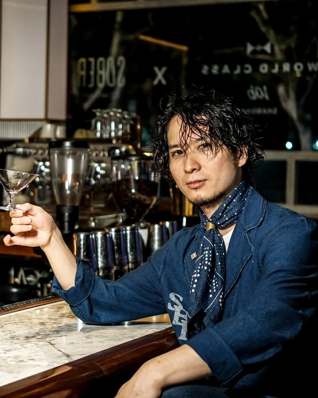 バーカウンターに座り、カクテルグラスを持つ男性