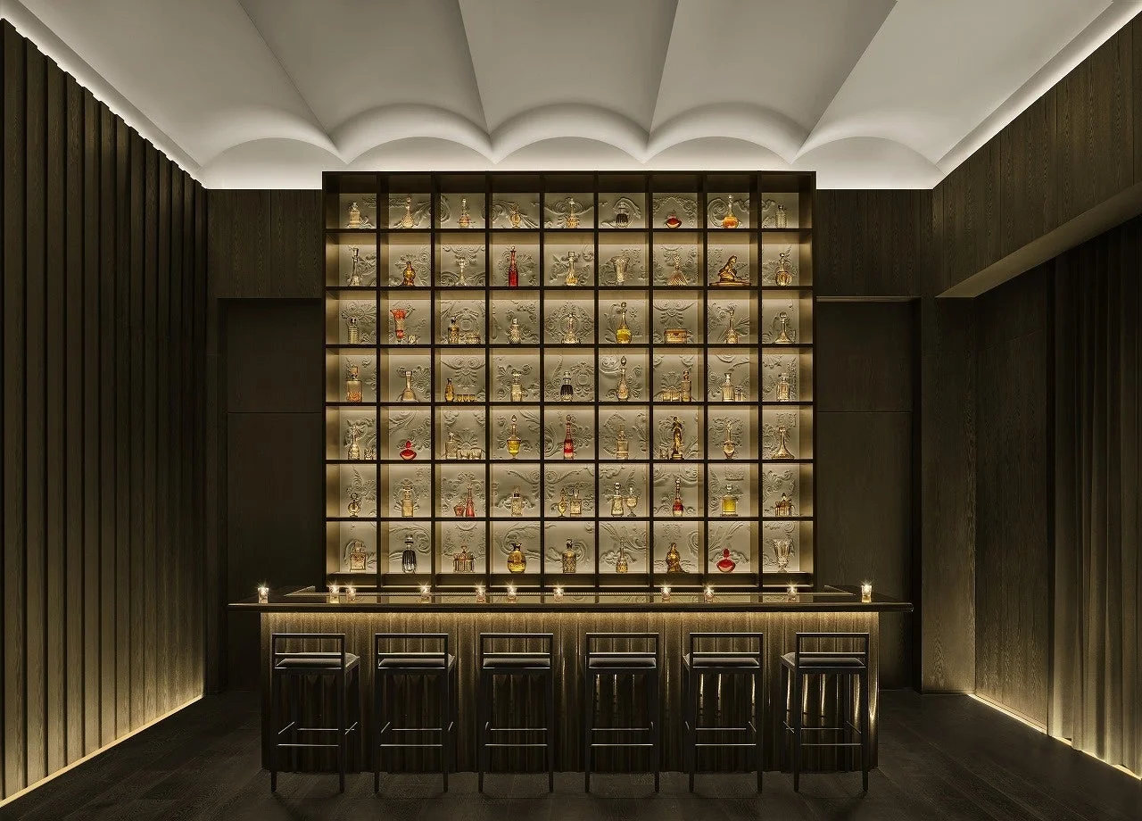 暗闇の中に浮かび上がるモダンなバーカウンターと、背後の壁一面に並べられた豪華なボトル