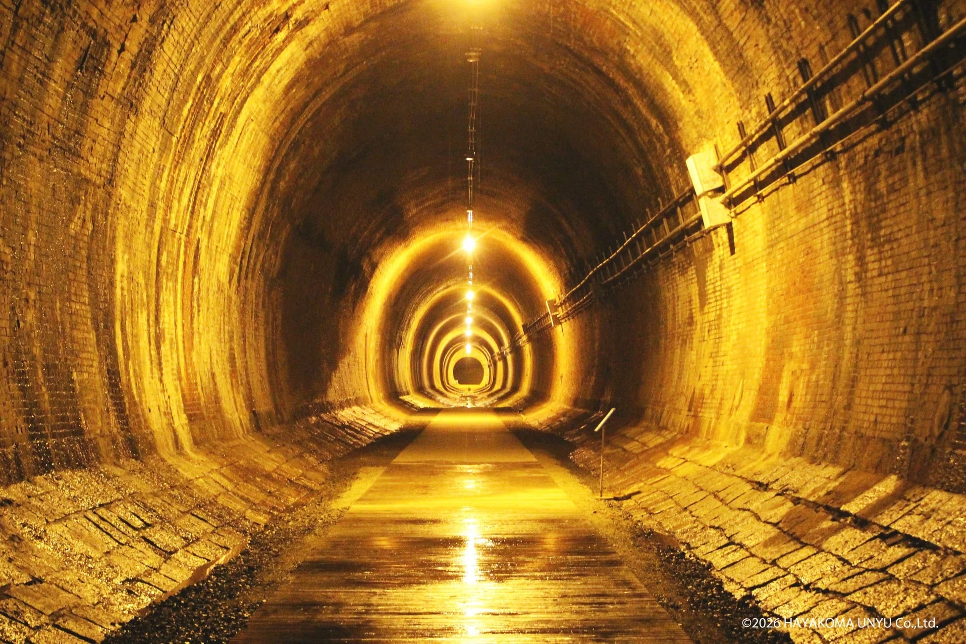 明るい光に照らされた、煉瓦造りの長いトンネルの内部です。