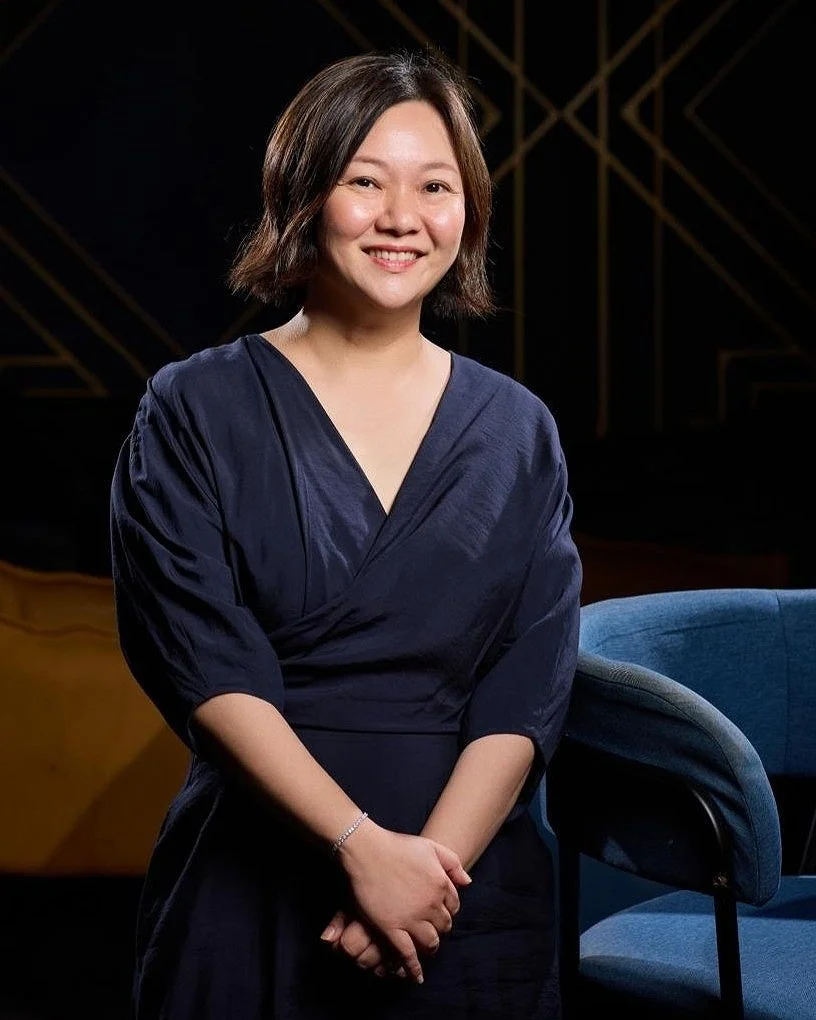 ネイビーの服を着用し笑顔で立つ女性