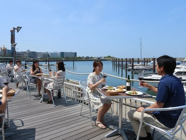 マリーナに面したテラス席で食事を楽しむ人々