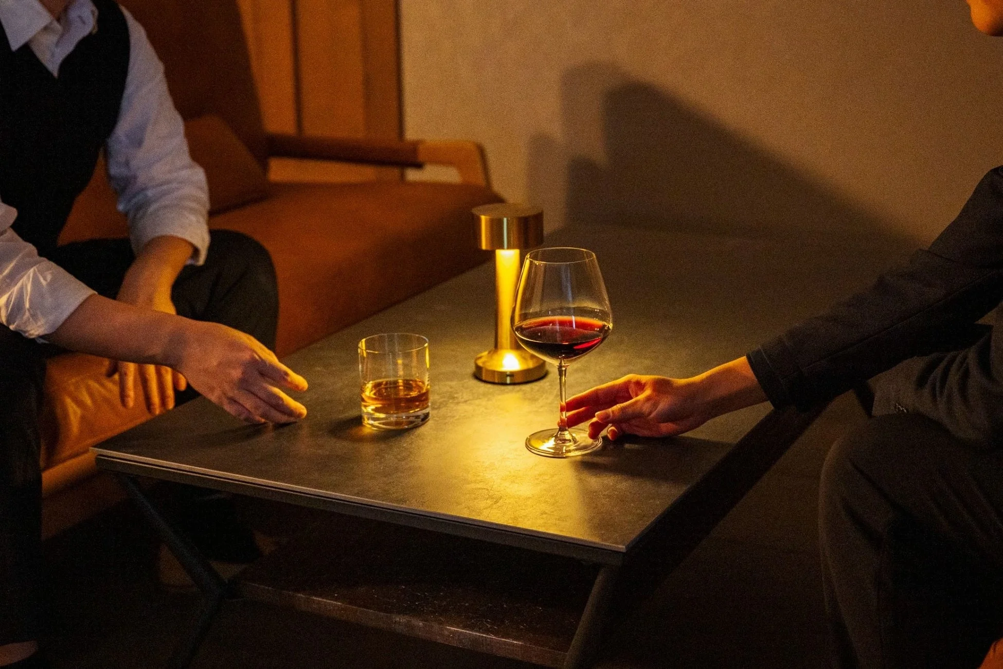 薄暗いバーのような空間で二人の人物がテーブルを挟んで向かい合っている