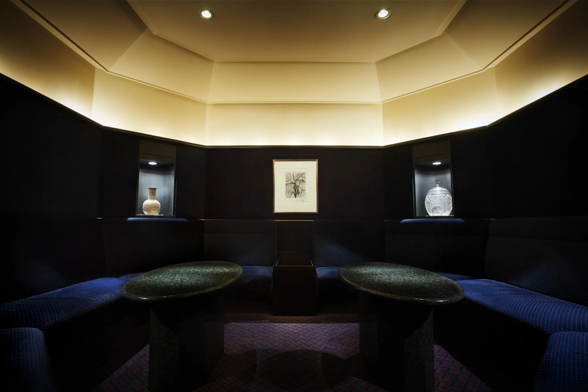 暗い青色のソファと楕円形のテーブルが配置された高級感のあるラウンジのような空間