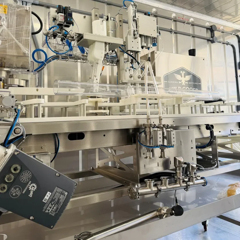 缶詰や瓶詰めの製造に使われる産業用充填機が写っています。ステンレス製の複雑な装置には、多くの配管や配線が見られ、自動化された生産ラインの一部であることが伺えます。