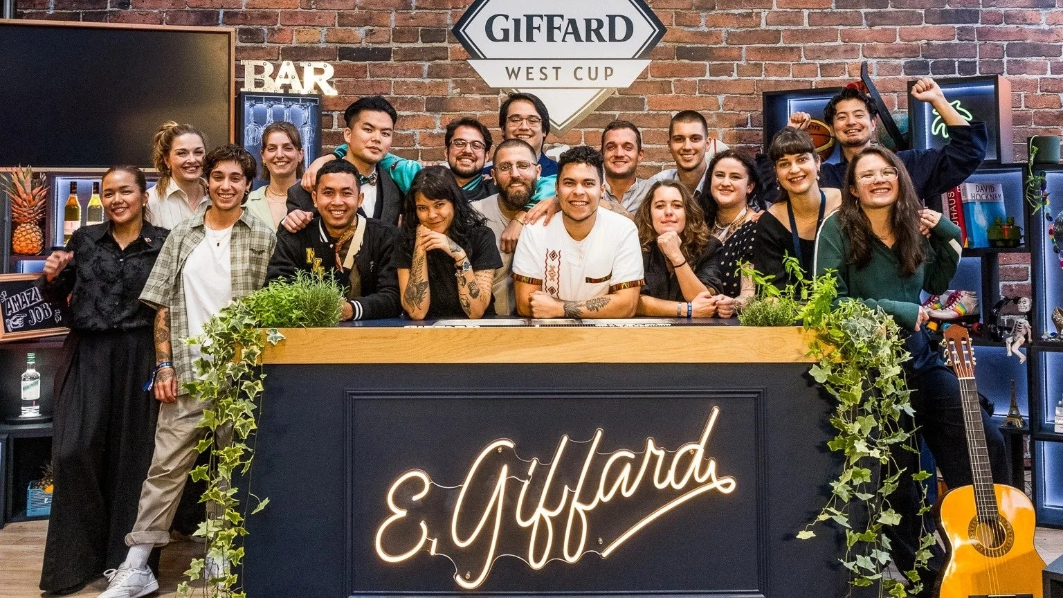 Giffard West Cupイベントに参加した多様な若い人々が、バーカウンターの後ろで笑顔でポーズをとっている集合写真