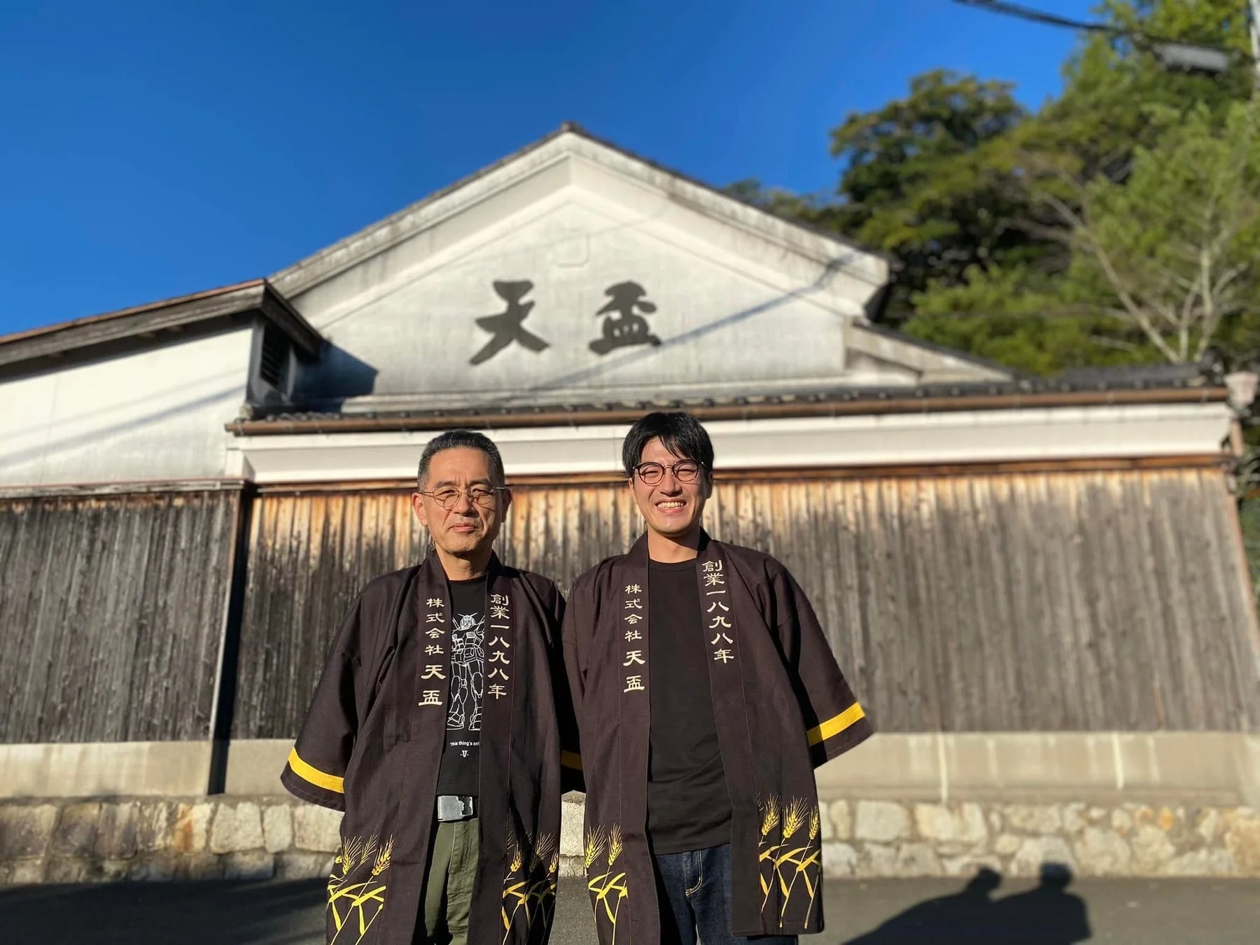 天盃のロゴが入った法被を着た二人の男性