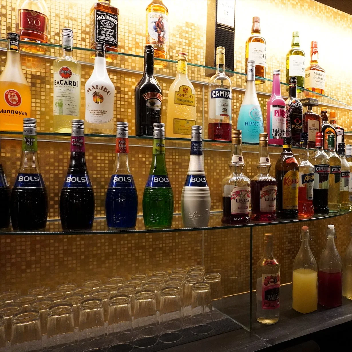 照明が当たったバーカウンターに並べられた酒やリキュールのボトル
