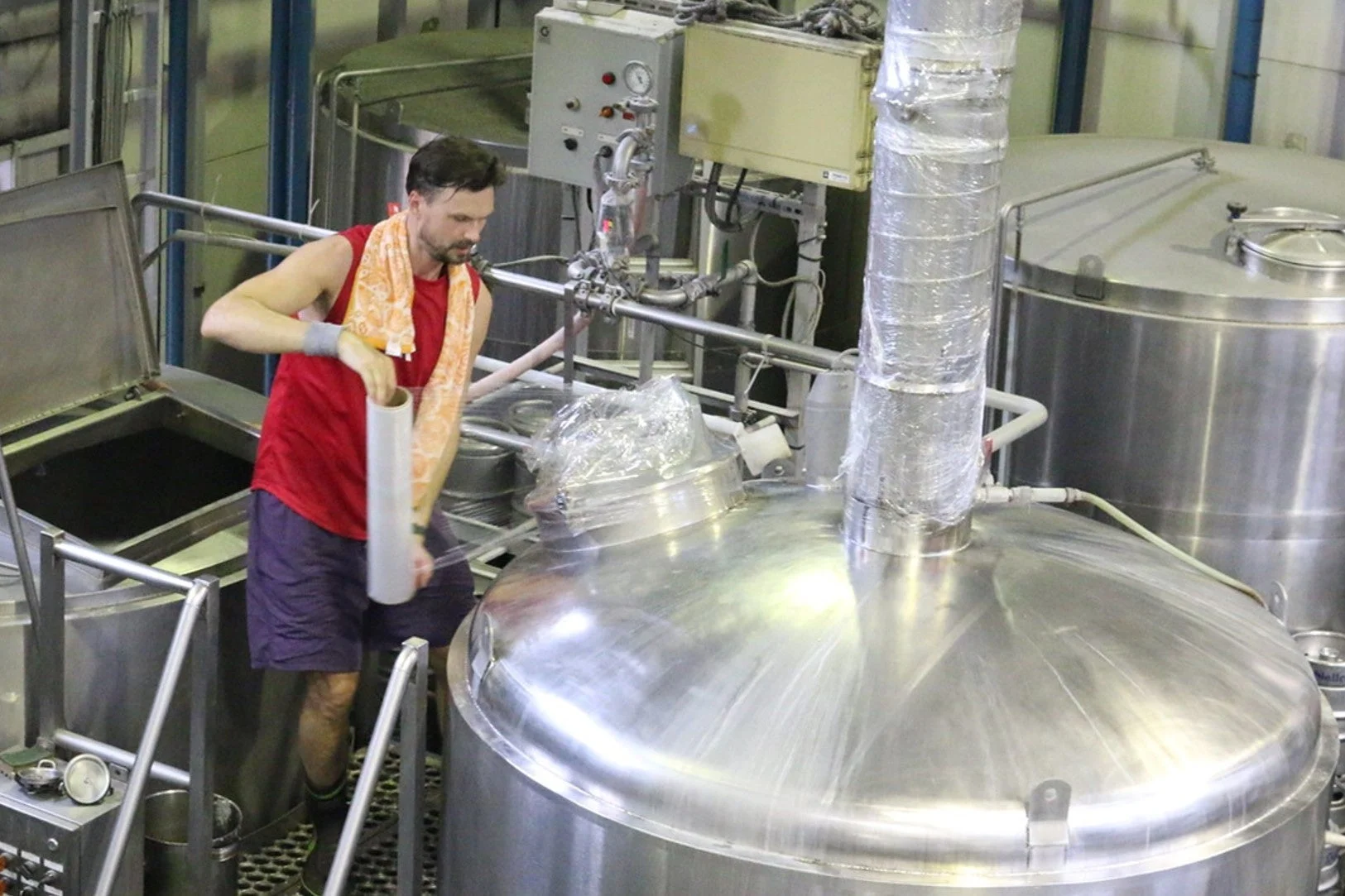 男性作業員が大型のステンレス製タンクのそばで作業