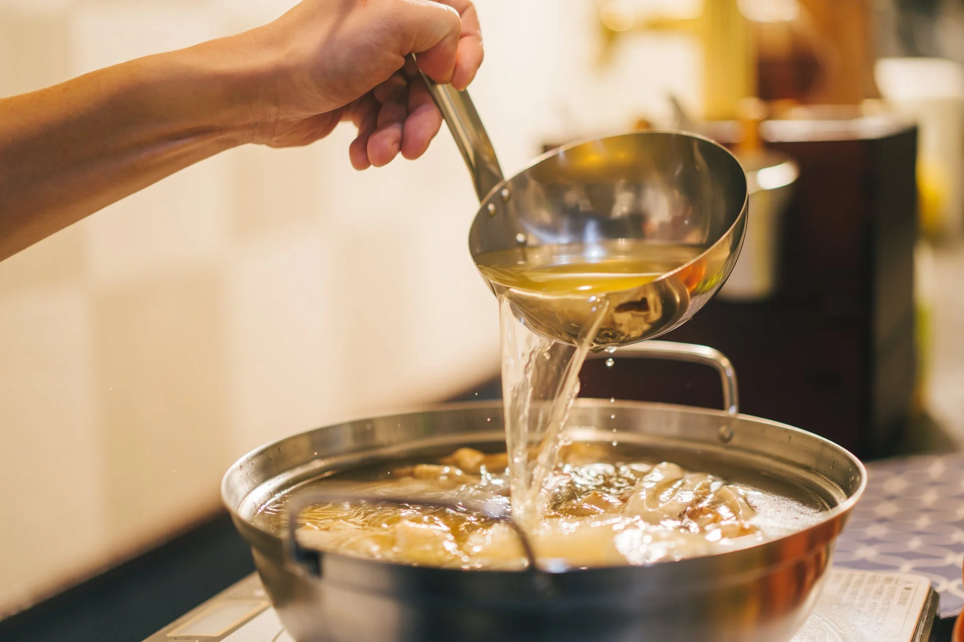 出汁を注ぐ手