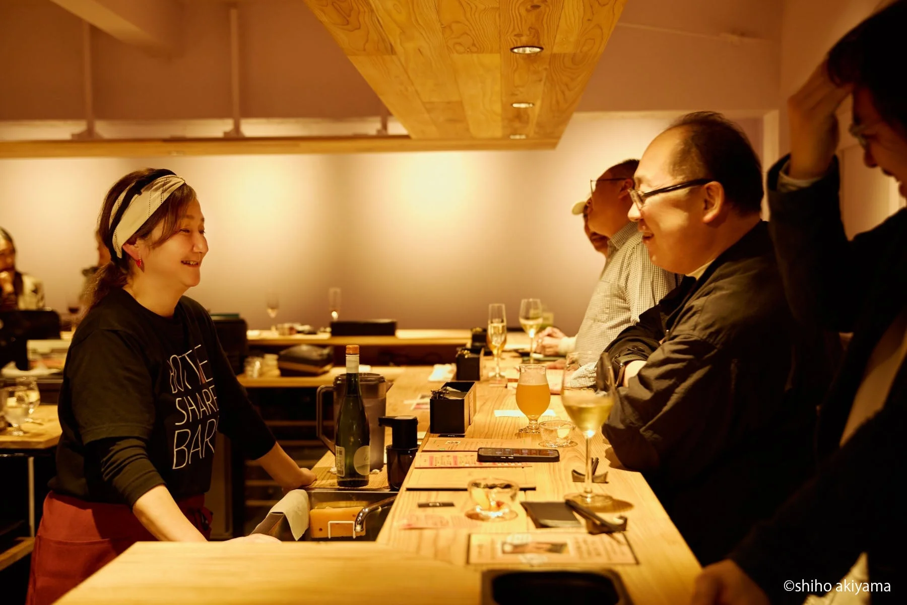 バーカウンターで談笑する店員と客