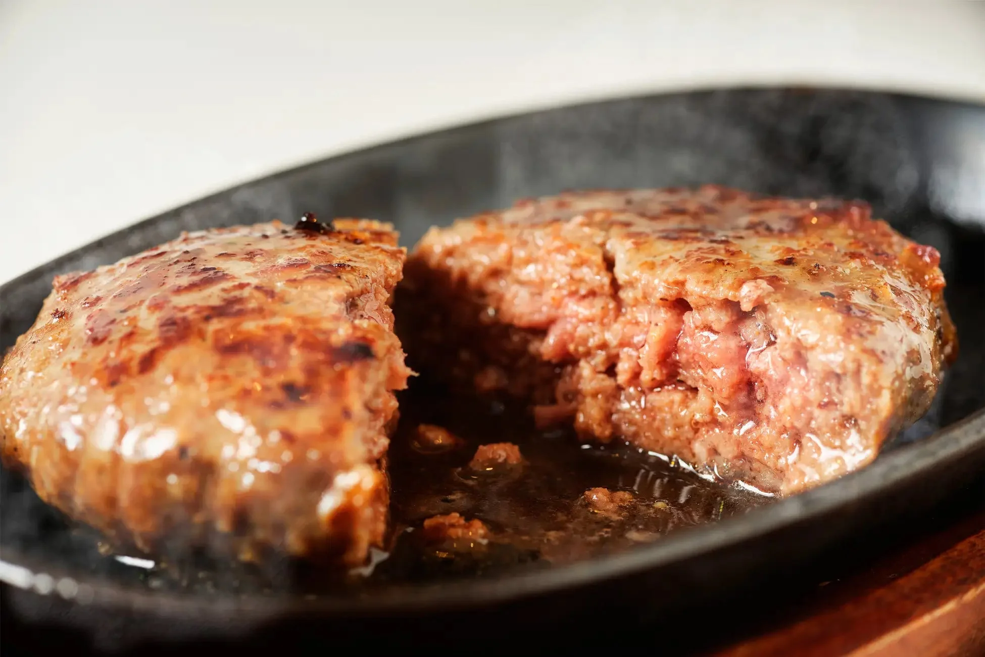 熱々の鉄板にのった、中央で半分にカットされたハンバーグ
