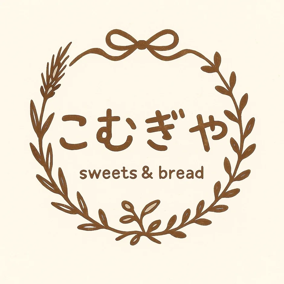 小麦の穂と葉、リボンで構成されたリースの中に「こむぎや sweets & bread」と書かれたロゴマーク