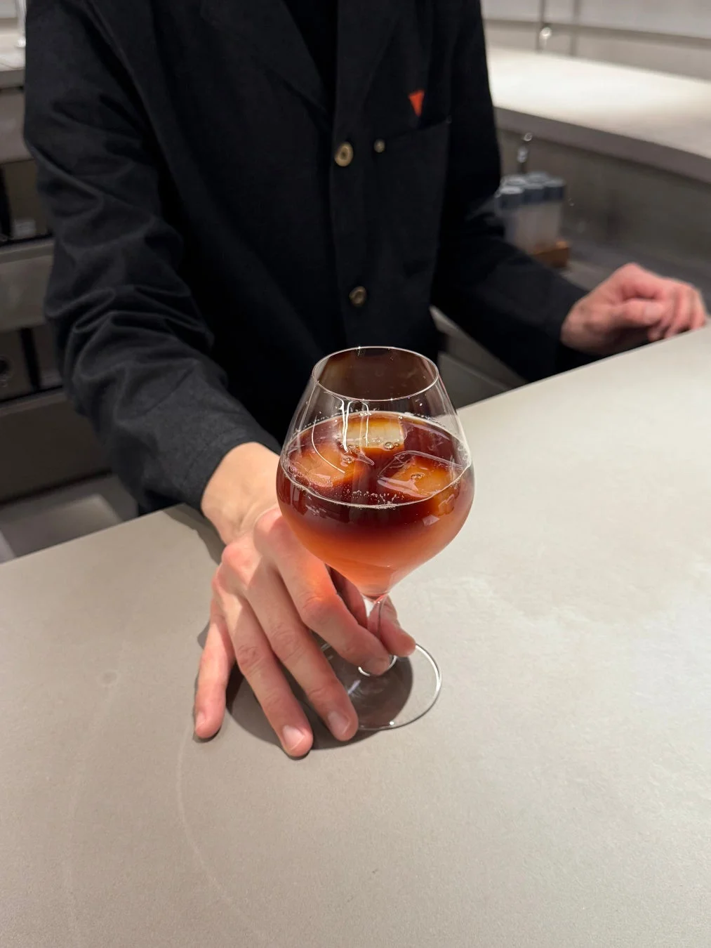 氷入りの赤いドリンクが入ったグラスをカウンターで提供している様子