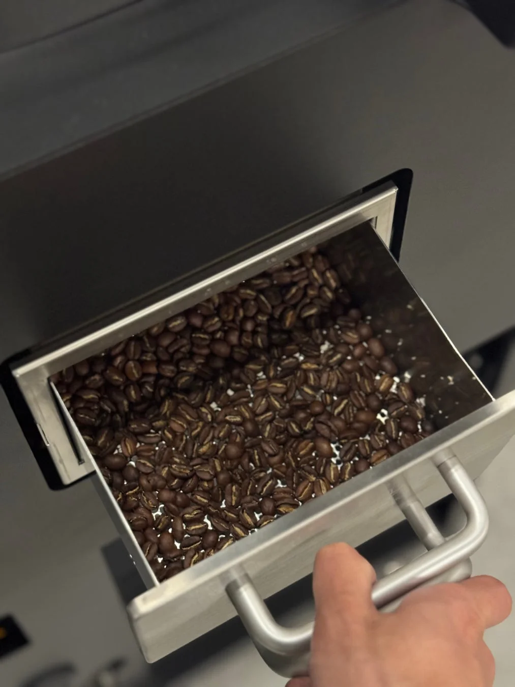 焙煎されたコーヒー豆がたっぷり入ったステンレス製のトレイ