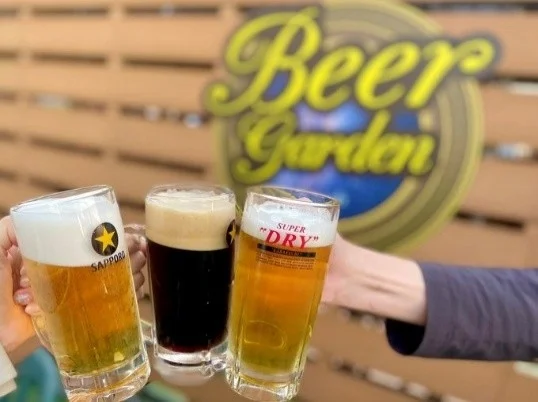 ビアガーデンで、サッポロビールとアサヒスーパードライを含む3種類のビールで乾杯している様子
