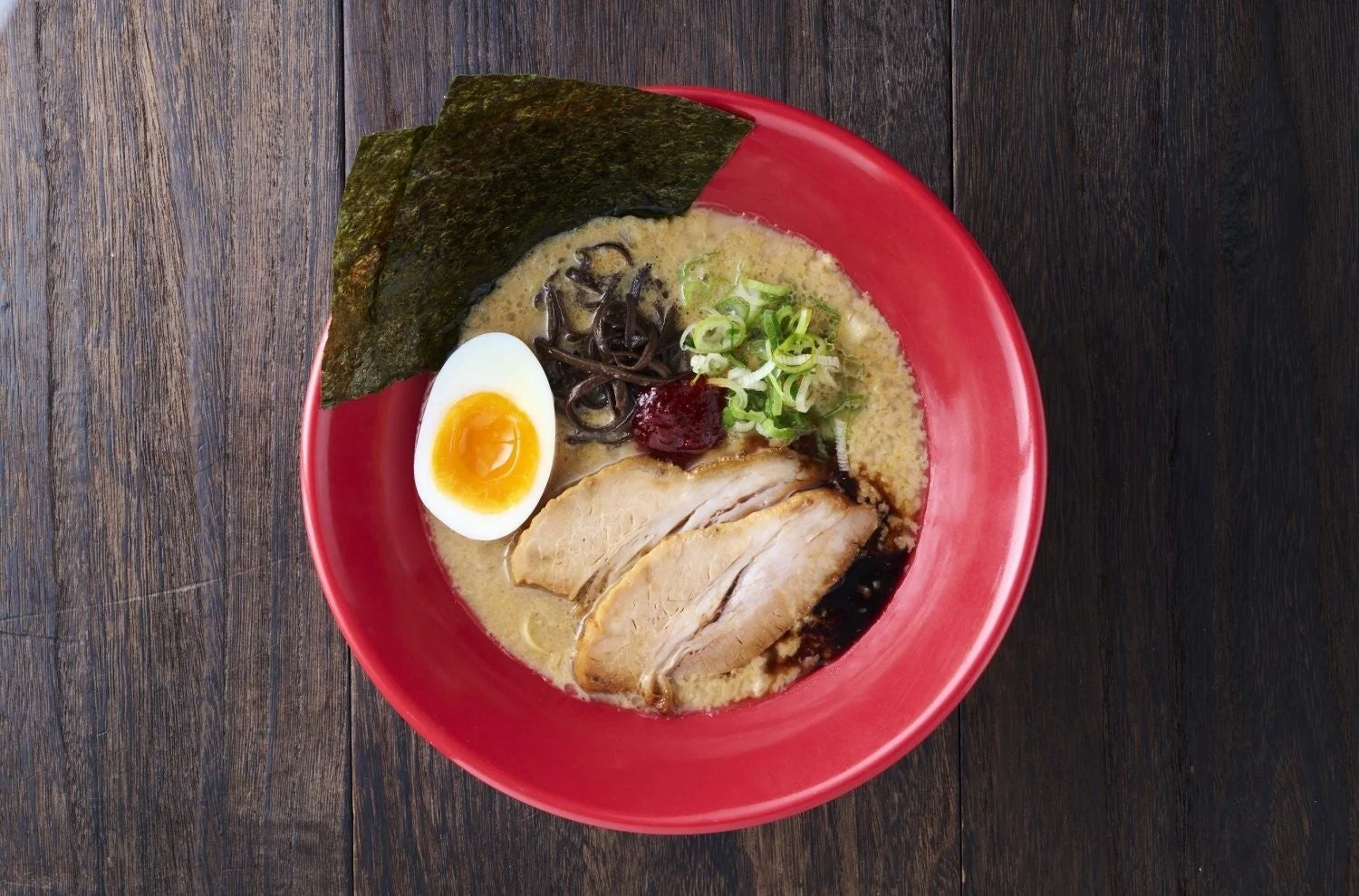 チャーシュー、味玉、海苔、キクラゲ、ネギ、辛味噌がトッピングされた濃厚な豚骨ラーメン